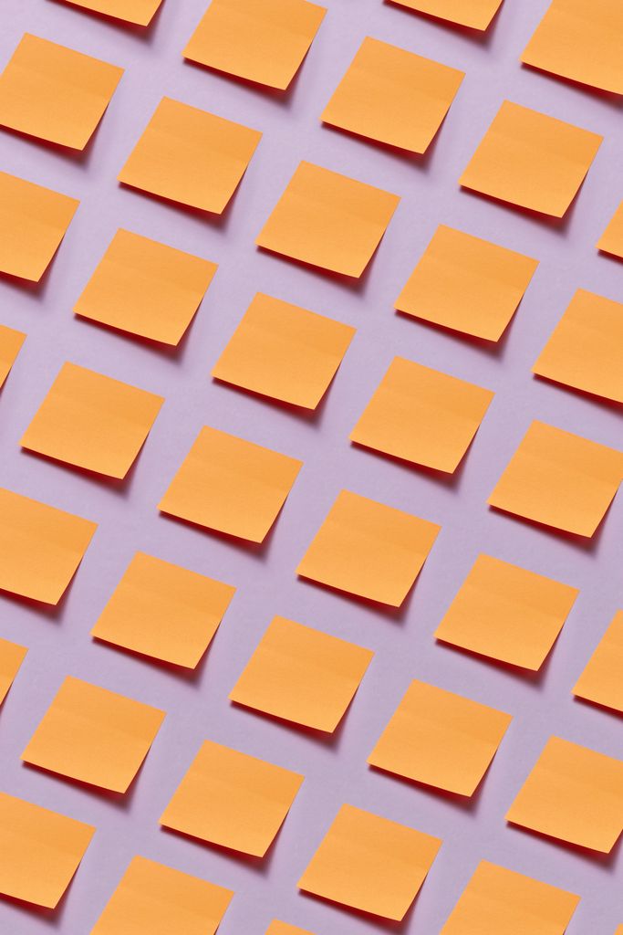 Rows of blank orange sticky notes arranged in a neat diagonal grid on a lavender surface, suggesting a plan broken into steps