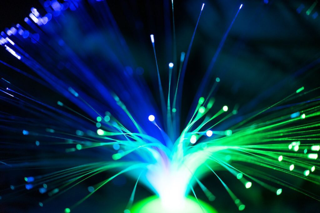 Fiber optic strands glowing blue and green against a dark background
