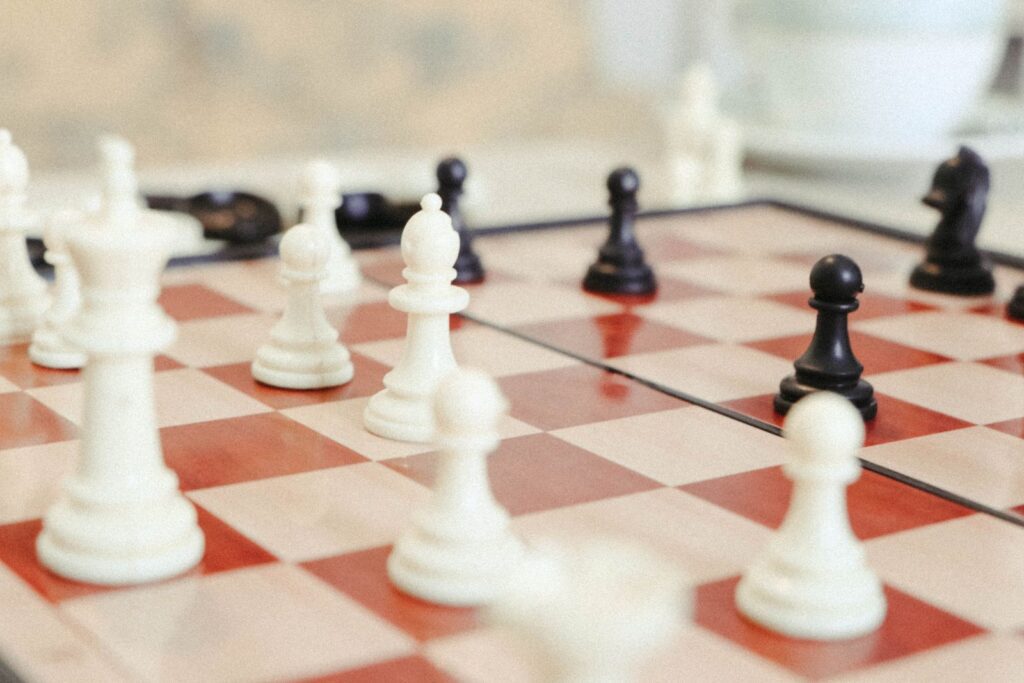 White and black chess pieces mid-game on a red and cream checkered board