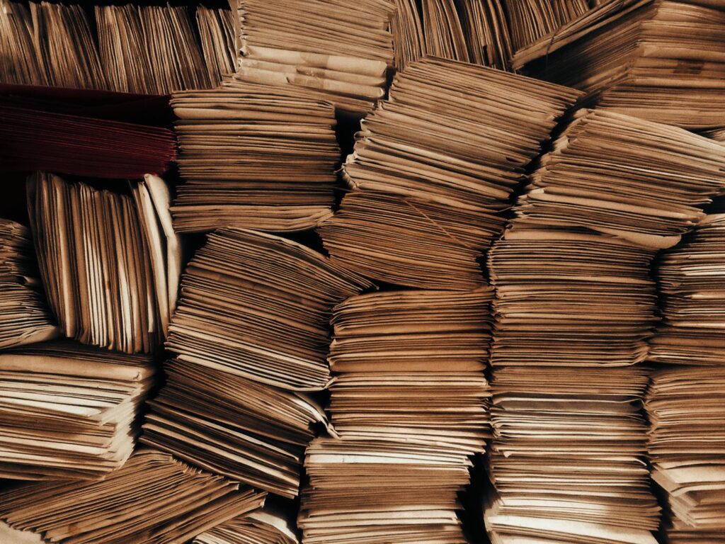 Large piles of old paper envelopes stacked in loose bundles