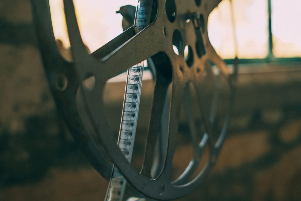 Close-up of a metal film reel with a strip of film near a window