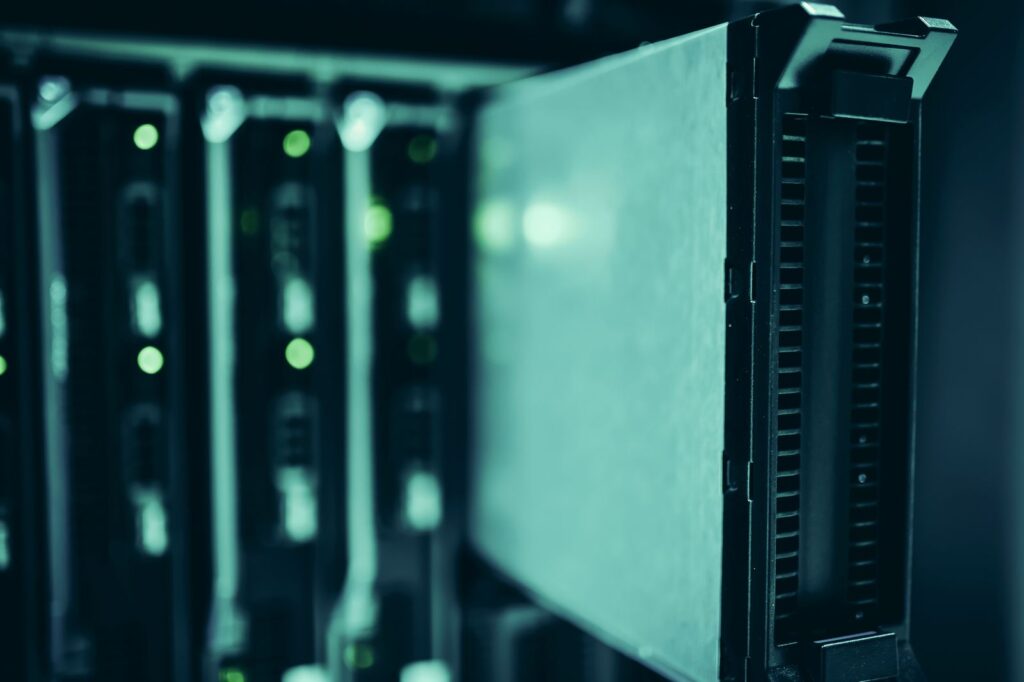 Close-up of server racks with small green status lights in a dim data center