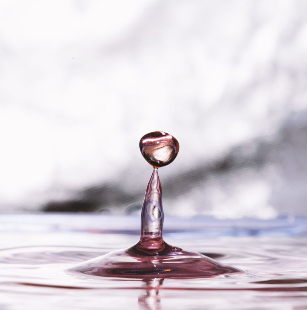 Single water drop rising from a pool and sending out gentle ripples