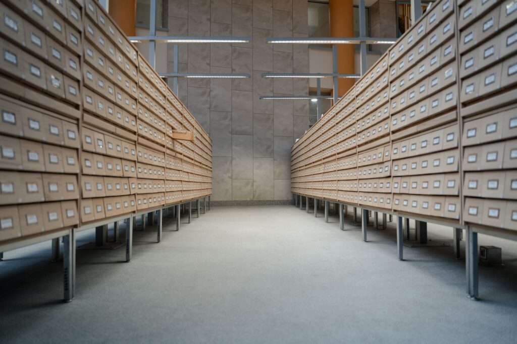 Long aisle between rows of wooden archive drawers under bright ceiling lights