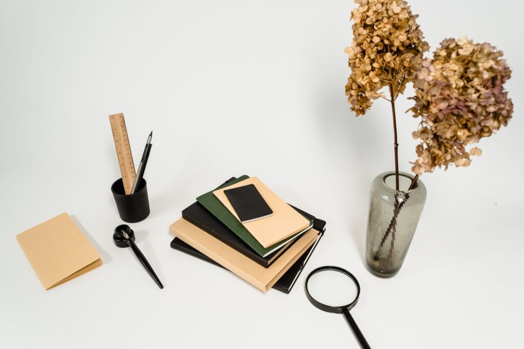 Stacked notebooks, a magnifying glass and a pencil cup on a white table