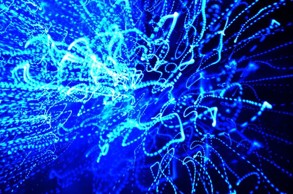 Bright blue light trails streaming and swirling across a dark background