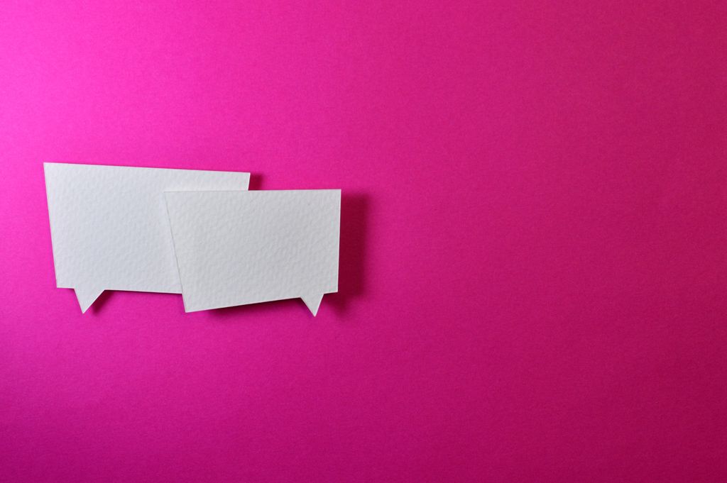 Two blank white speech bubble cutouts on a vivid magenta background